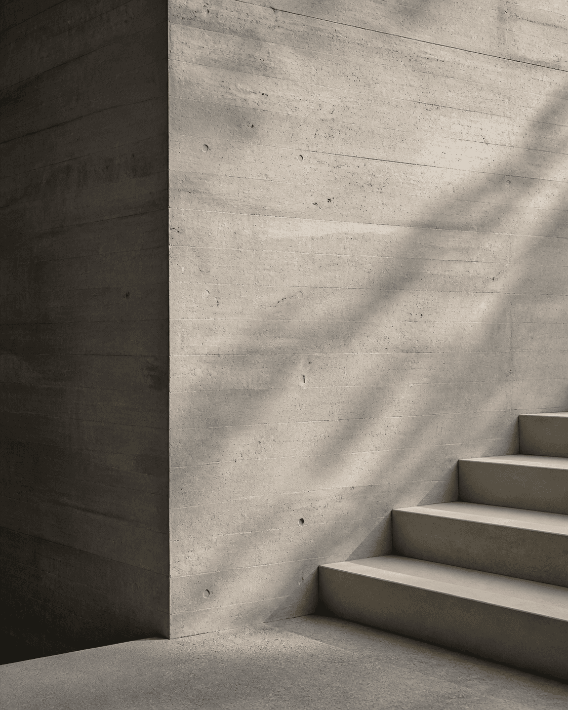 Muro y escalera de concreto expuesto iluminados por luz natural